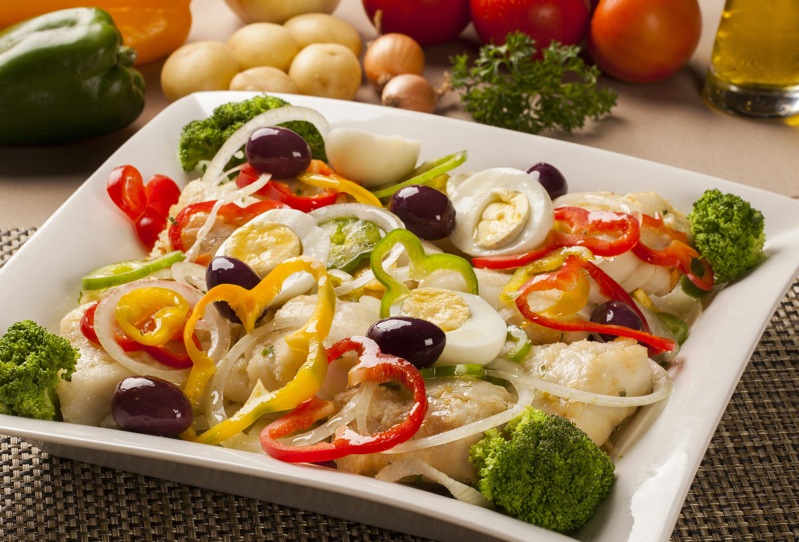 Codfish - fish fillet in sauce and vegetables on the table.